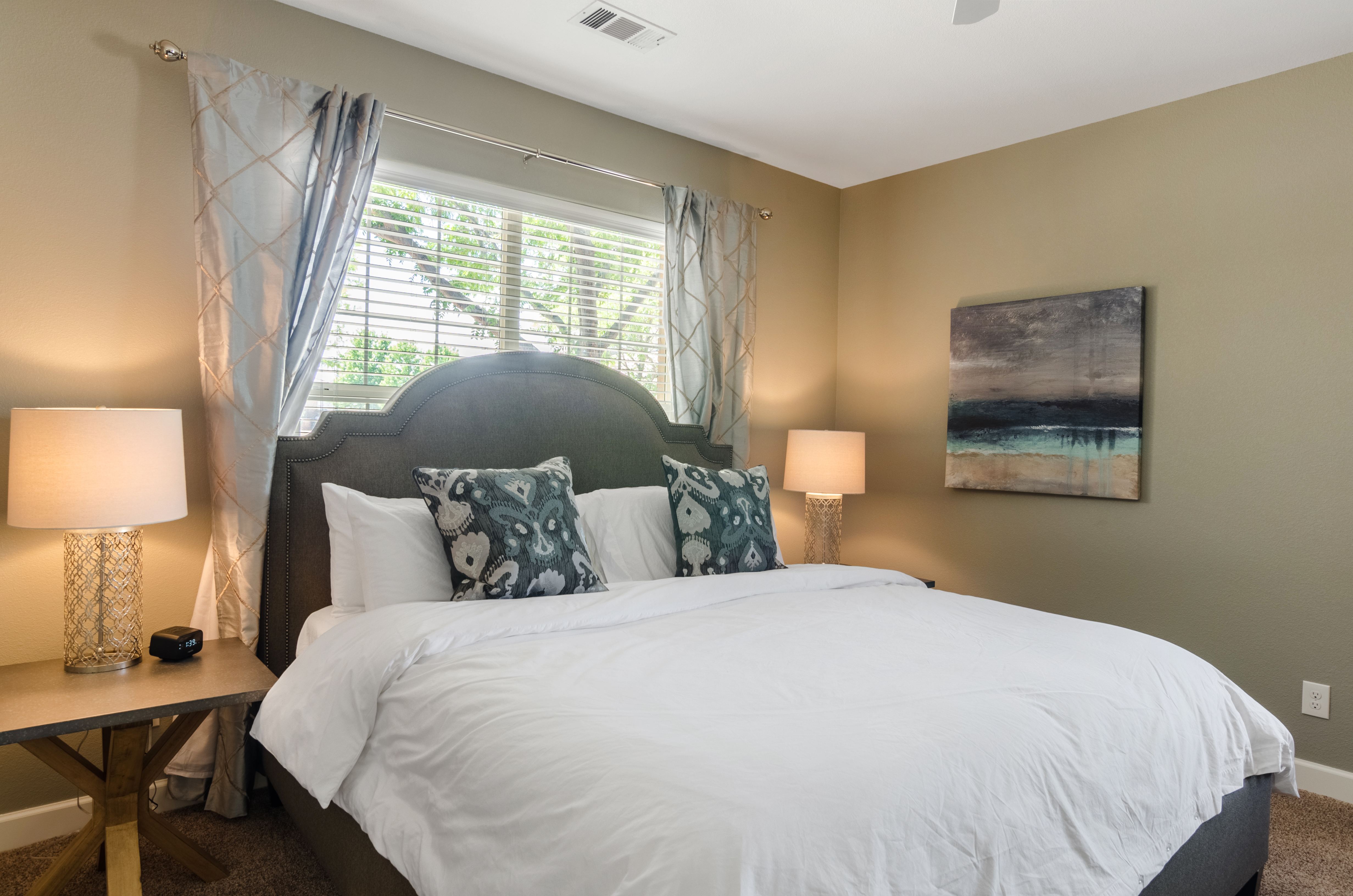 A bedroom with a large bed and a painting on the wall.
